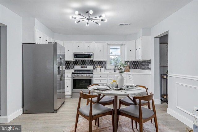 1711 Langley Rd, Baltimore, MD 21221 - kitchen featuring appliances with stainless steel finishes, a chandelier, decorative backsplash, and light wood-style flooring
