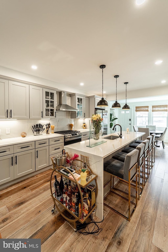 1919 Bennett Pl NE, Washington, DC 20002 - kitchen featuring wall chimney exhaust hood, stainless steel range with gas cooktop, a kitchen breakfast bar, a sink, and light wood-style floors