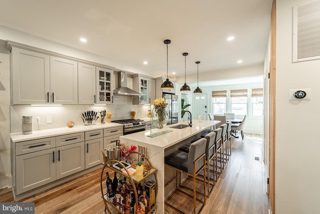 1919 Bennett Pl NE, Washington, DC 20002 - kitchen featuring wall chimney range hood, gray cabinets, appliances with stainless steel finishes, a sink, and light wood finished floors