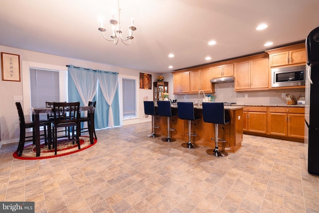 1722 Bradley Dr, Harrisburg, PA 17110 - kitchen with stainless steel microwave, under cabinet range hood, a chandelier, recessed lighting, and an island with sink