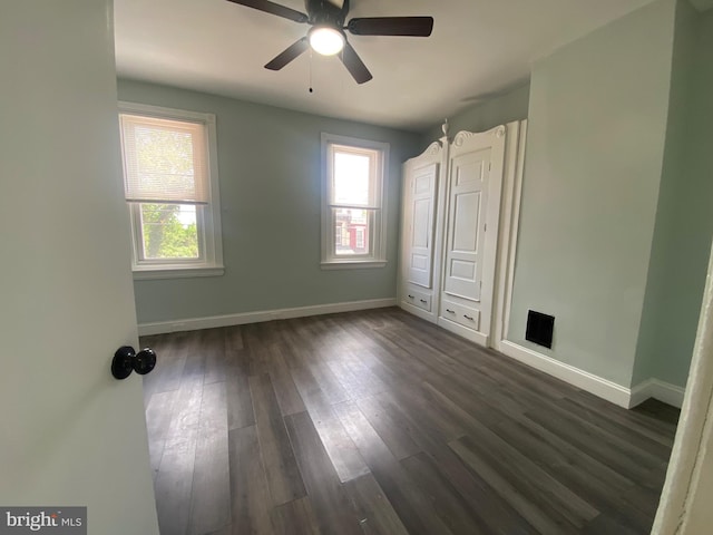 unfurnished bedroom featuring dark wood-type flooring, baseboards, and a ceiling fan