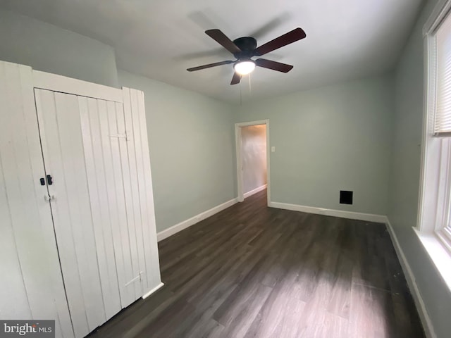 unfurnished bedroom with dark wood finished floors, baseboards, and a ceiling fan