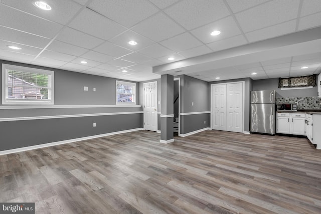 1223 Kendrick Rd, Baltimore, MD 21237 - basement featuring freestanding refrigerator, wood finished floors, healthy amount of natural light, baseboards, and a paneled ceiling