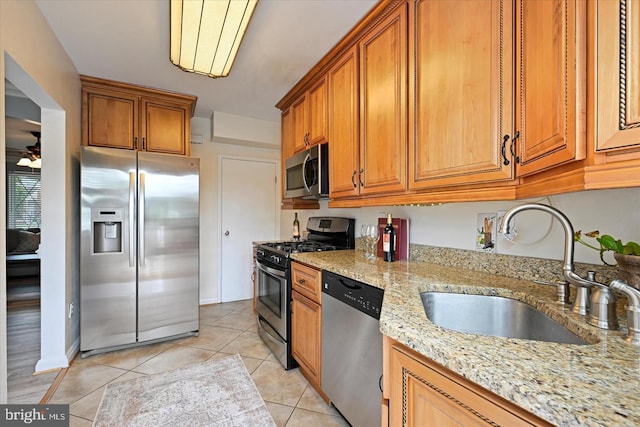 7849 Charlesmont, Dundalk, MD 21222 - kitchen featuring appliances with stainless steel finishes, a sink, brown cabinets, light stone counters, and light tile patterned flooring