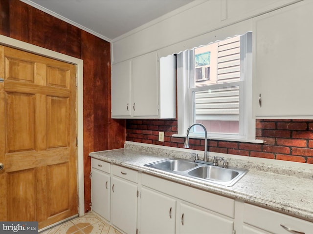 kitchen with a sink, light countertops, ornamental molding, and white cabinetry