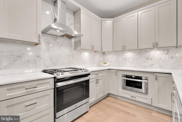4324 14th St NW Unit 1, Washington, DC 20011 - kitchen with appliances with stainless steel finishes, wall chimney exhaust hood, light wood-style flooring, and decorative backsplash