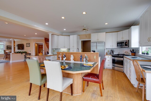 46369 Hattons Rest Ln, Lexington Park, MD 20653 - kitchen featuring appliances with stainless steel finishes, decorative columns, crown molding, white cabinetry, and light wood-type flooring