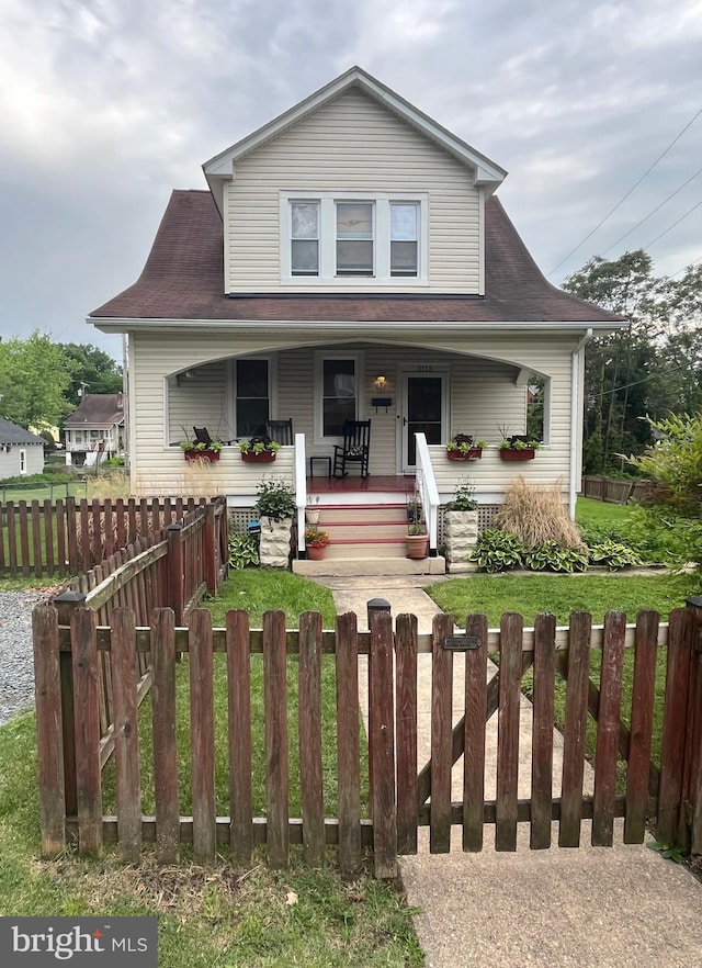 view of front facade featuring covered porch and a fenced front yard