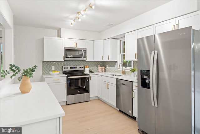 kitchen featuring appliances with stainless steel finishes, a sink, backsplash, and white cabinets