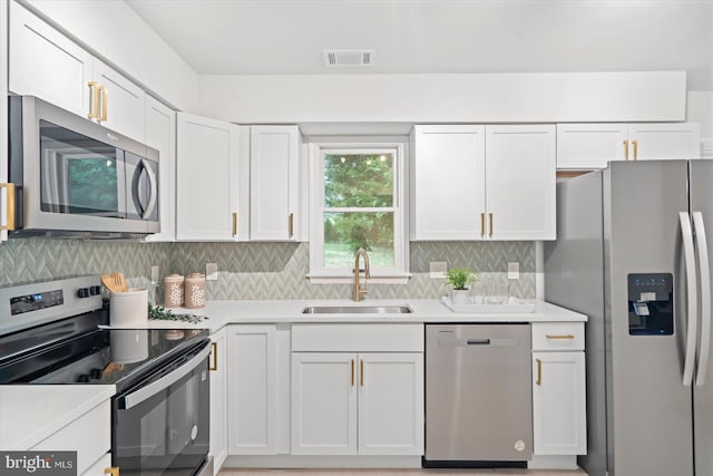 kitchen with stainless steel appliances, a sink, white cabinets, and light countertops