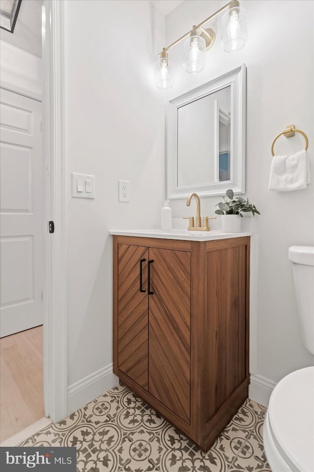 half bath featuring toilet, baseboards, vanity, and tile patterned floors