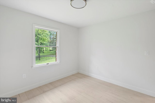 empty room featuring light wood finished floors, plenty of natural light, and baseboards