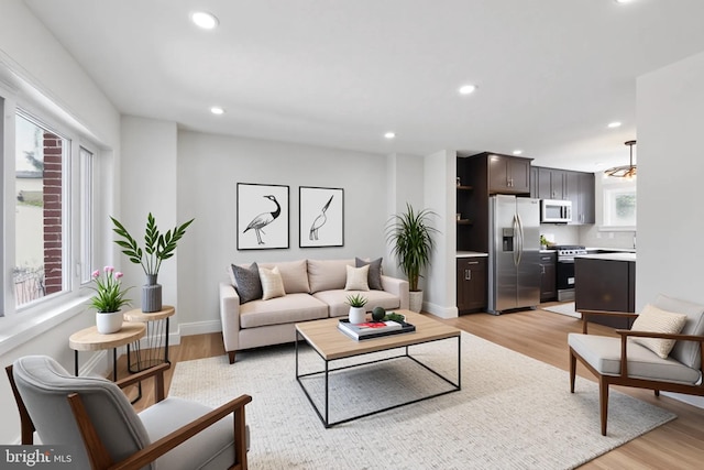 living room with light wood-style floors, recessed lighting, and baseboards