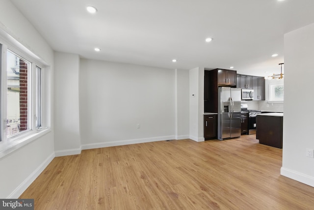 unfurnished living room with light wood-style flooring, recessed lighting, a chandelier, and baseboards