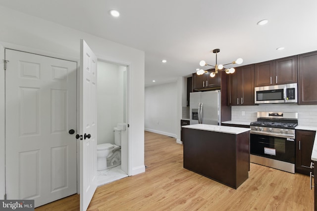 kitchen with stainless steel appliances, a chandelier, a center island, dark brown cabinets, and decorative backsplash