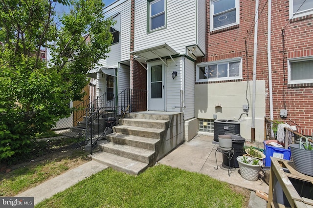 view of exterior entry with cooling unit and brick siding