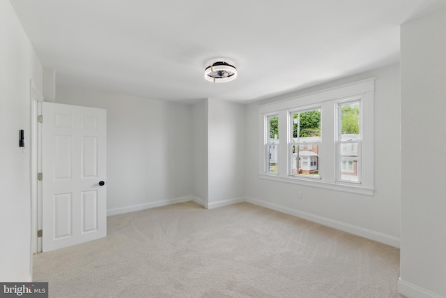 spare room with light colored carpet and baseboards