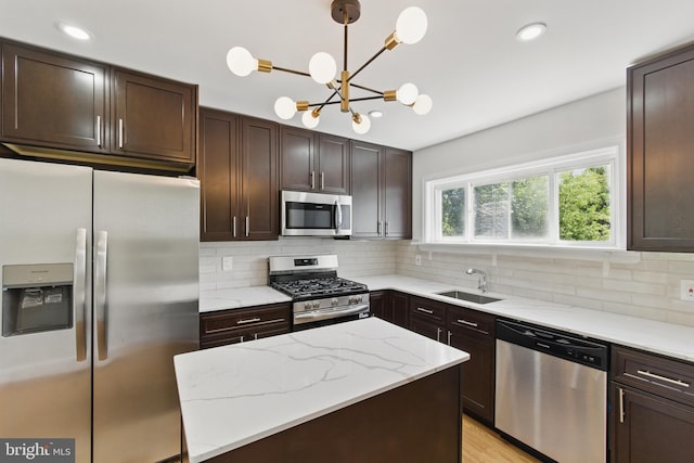 kitchen featuring stainless steel appliances, a sink, dark brown cabinets, decorative backsplash, and a chandelier