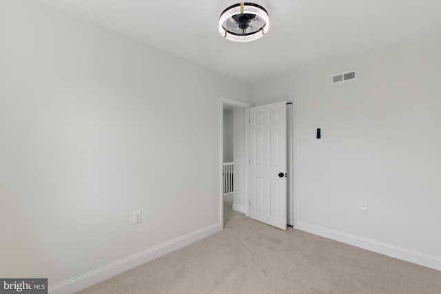 spare room featuring light colored carpet and baseboards