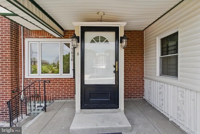 property entrance featuring brick siding and covered porch