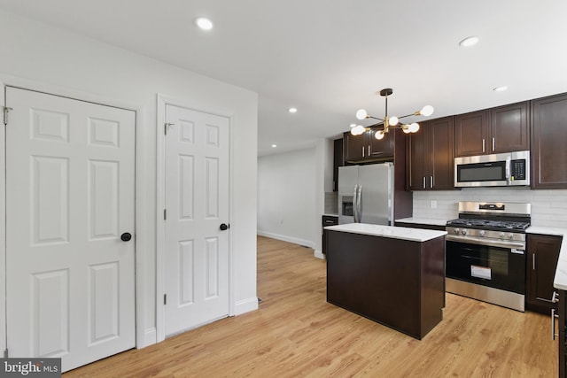 kitchen featuring appliances with stainless steel finishes, a center island, dark brown cabinets, a chandelier, and decorative backsplash