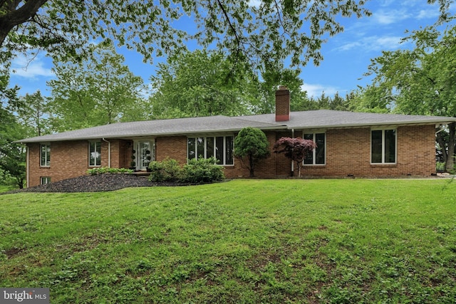 ranch-style house featuring a chimney, a front yard, and brick siding