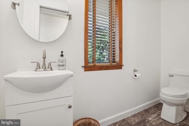 half bath featuring baseboards, vanity, marble finish floors, and toilet