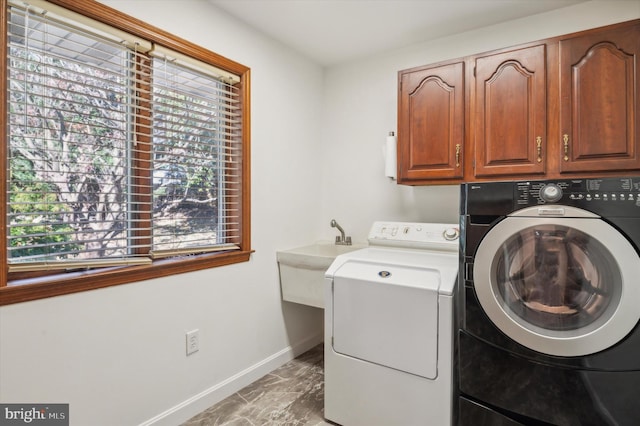 laundry room featuring separate washer and dryer, cabinet space, light marble finish floors, and baseboards