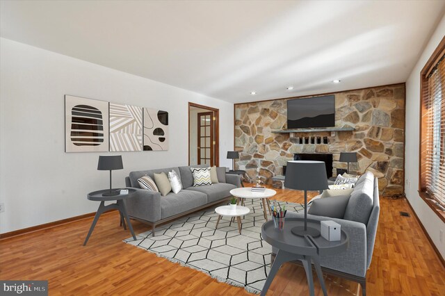 living area featuring wood finished floors, a stone fireplace, baseboards, and recessed lighting