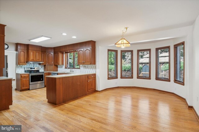 kitchen featuring stainless steel electric range, light countertops, a peninsula, light wood finished floors, and recessed lighting