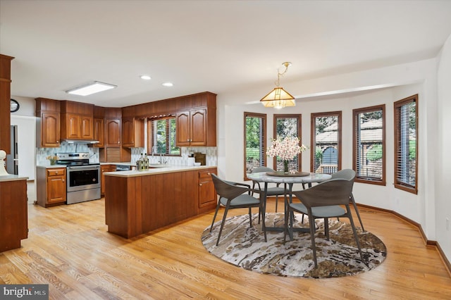 kitchen featuring stainless steel electric range, backsplash, light countertops, a peninsula, and recessed lighting