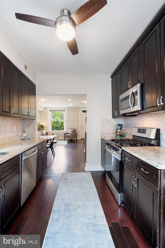 kitchen with stainless steel appliances, a ceiling fan, open floor plan, dark wood finished floors, and decorative backsplash