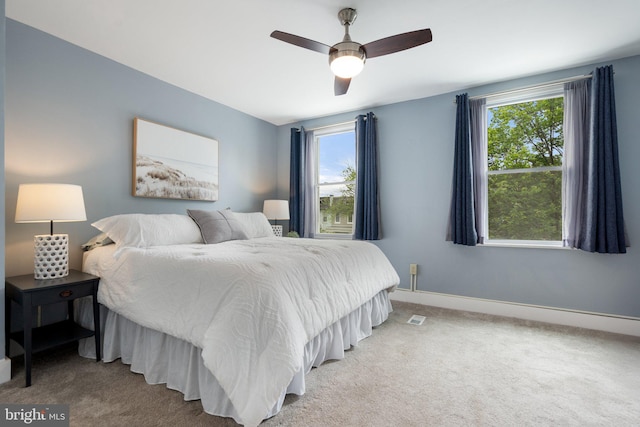bedroom featuring light colored carpet, baseboards, and a ceiling fan