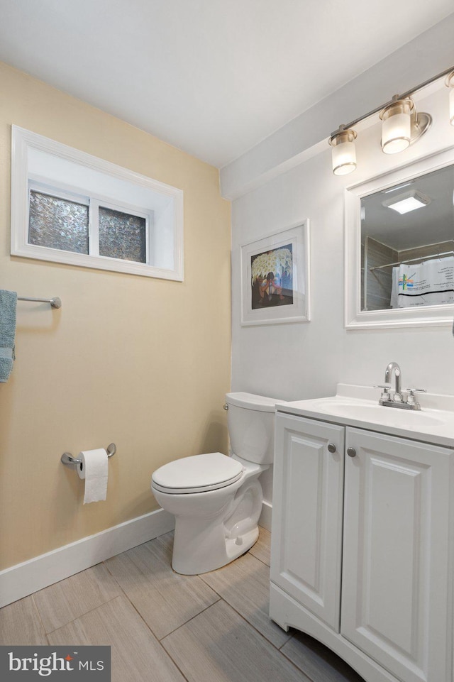 bathroom featuring toilet, baseboards, vanity, and a shower with shower curtain