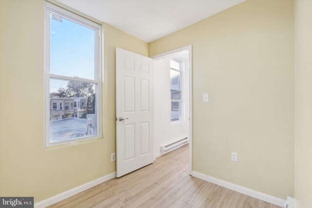 702 Main St, Darby, PA 19023 - unfurnished bedroom with baseboard heating, light wood-style flooring, baseboards, and a baseboard heating unit