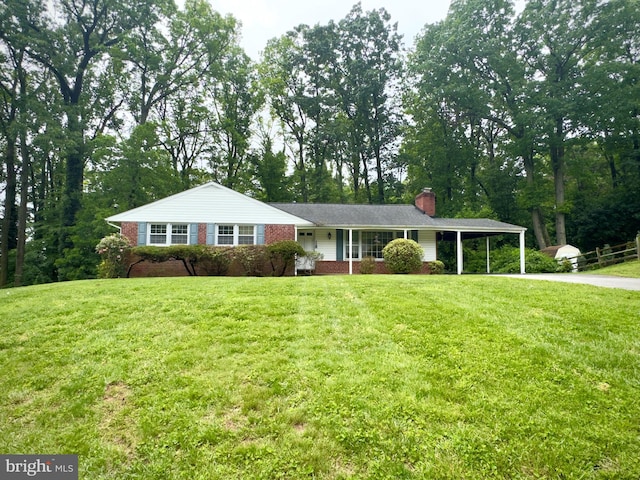single story home with a chimney, concrete driveway, a carport, and a front lawn
