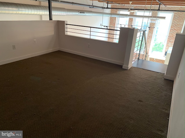 unfurnished room featuring baseboards and dark carpet