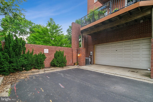 800 S Charles St, Baltimore, MD 21230 - view of home's exterior featuring brick siding, a garage, cooling unit, asphalt driveway, and a balcony