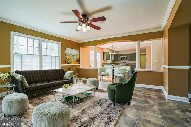 living room with ornate columns, a ceiling fan, ornamental molding, baseboards, and a chandelier