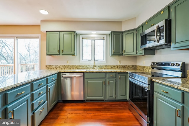 kitchen with appliances with stainless steel finishes, a sink, plenty of natural light, dark wood-style flooring, and recessed lighting