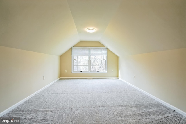 additional living space featuring carpet flooring, vaulted ceiling, and baseboards