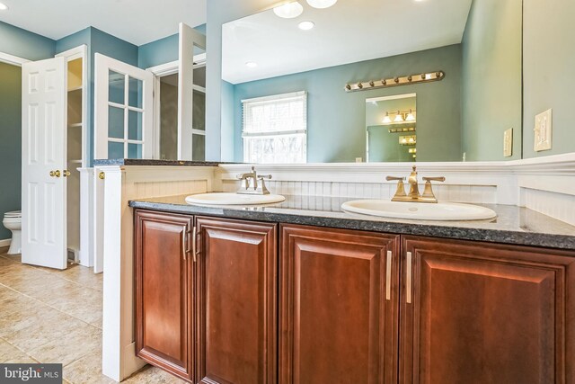 full bath featuring double vanity, toilet, and tile patterned flooring
