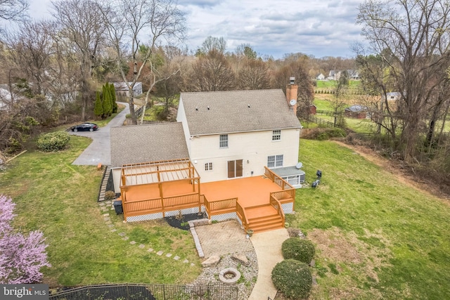 rear view of property with a wooden deck, a chimney, a lawn, and stairway