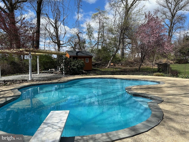 view of pool featuring a pergola, fence, an outbuilding, a patio, and a diving board