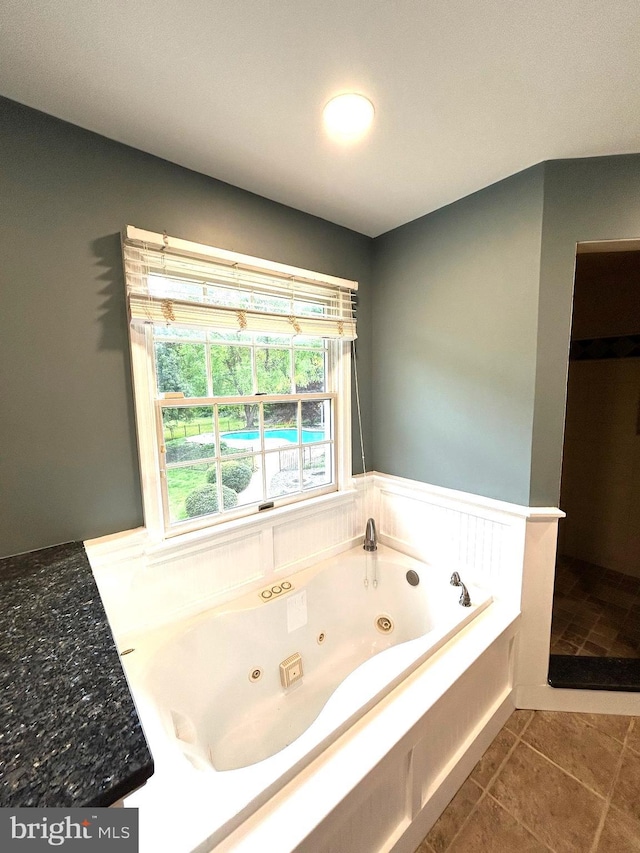 bathroom with wainscoting, a tub with jets, and tile patterned flooring