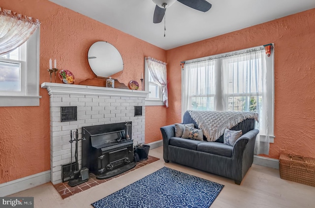 6126 Taylor St, Chincoteague Island, VA 23336 - living area featuring a textured wall, plenty of natural light, baseboards, a ceiling fan, and a brick fireplace