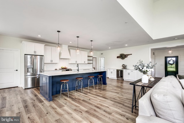3471 Bullfrog Rd, Taneytown, MD 21787 - kitchen with stainless steel fridge with ice dispenser, a breakfast bar area, white cabinetry, custom exhaust hood, and light wood-style floors
