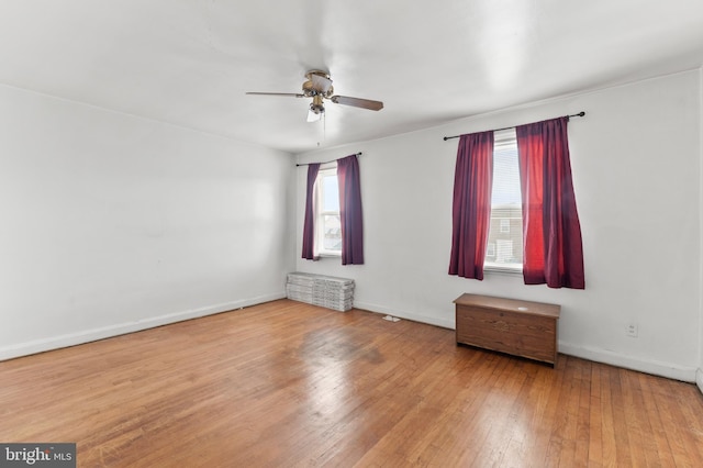 unfurnished room featuring a ceiling fan, hardwood / wood-style flooring, and baseboards