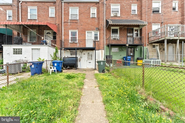 rear view of property featuring heating fuel, fence, central air condition unit, and brick siding