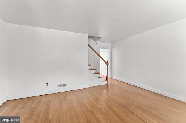 spare room with stairway, wood finished floors, and baseboards